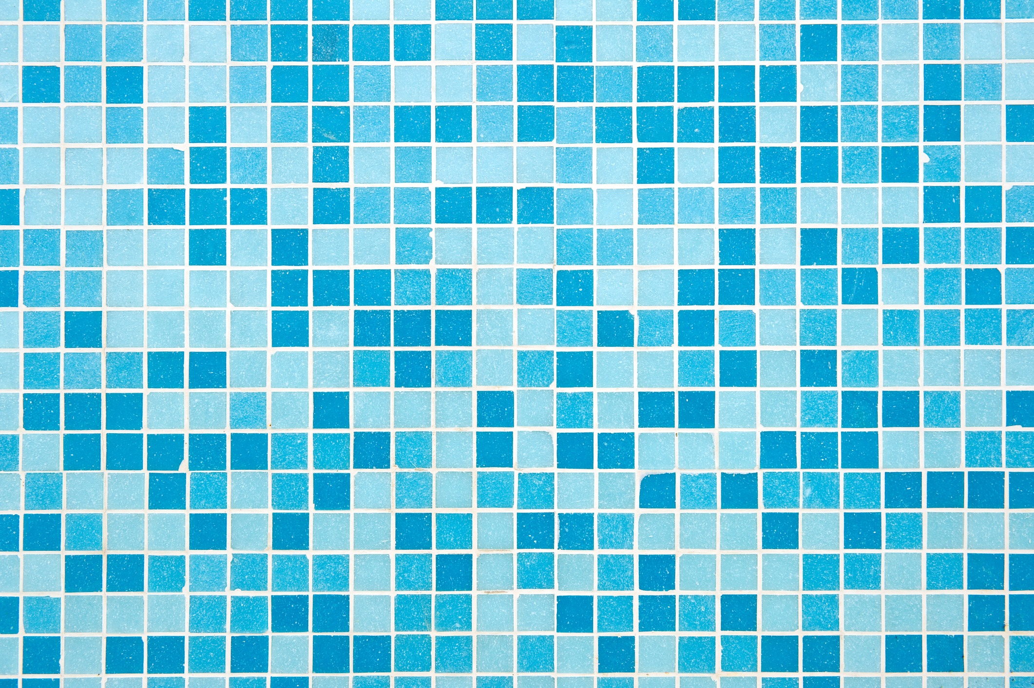 A photograph featuring a blue mosaic tile pattern, showcasing various shades of blue squares, creating an artistic and geometric visual effect.